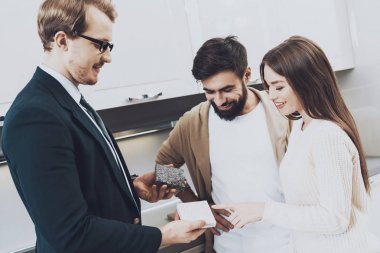 Çift istemcilerine mutfak mağazasında farklı malzeme gösterilen takım yöneticisi