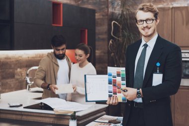 Mutfak mağazasında arka plan üzerinde renkli renk örnekleri ve planları çift müşterileri ile gösterilen takım yöneticisi