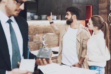 Çift müşterileri ile farklı malzemeleri mutfak mağazasında arka plan üzerinde gösterilen takım yöneticisi