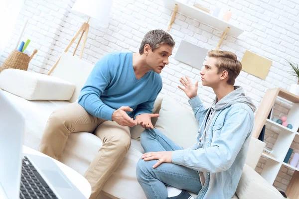 Father and son sitting on sofa and arguing with each other