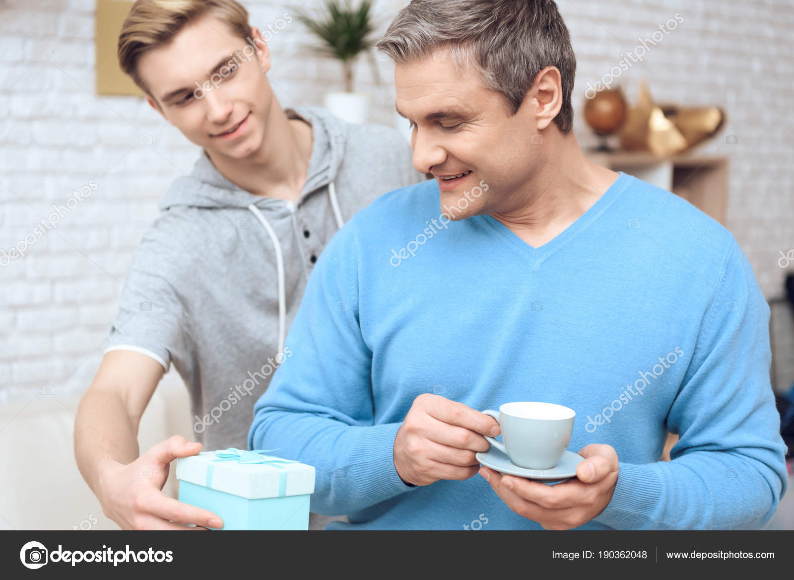 Father Drinking Coffee While Son Surprising Him Birthday Present Stock