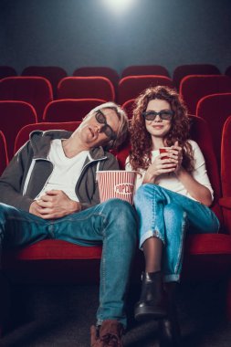 Adam ve kadın oturmuş film izliyorlar.