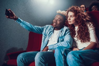 Adam gülümser ve sinemada bir kızla selfie çeker..