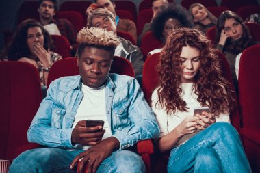 Çift sinemada oturmuş telefonlara bakıyor..