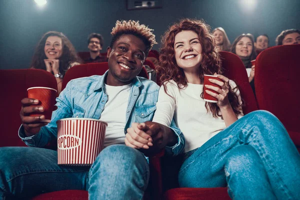 Молода пара сидить у кіно і тримає руки . — стокове фото