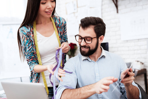 Женщина показывает мужчине красочные ленты в портной
