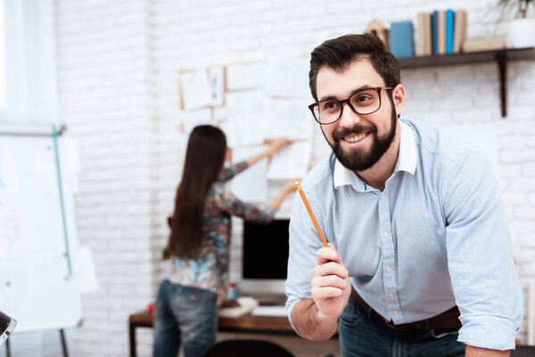 male designer having idea of sketch while woman working with orders in tailor shop 