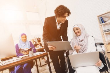 Arap kadın ile erkek iş arkadaşınız konuşuyor tekerlekli sandalyede hijab devre dışı