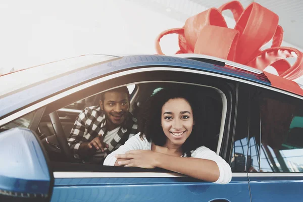 African american family in car dealership, mother and father sitting in saloon of new car