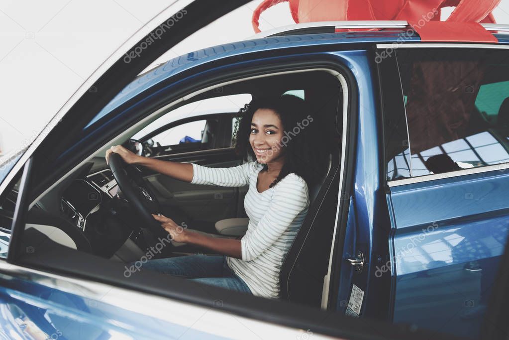 African american woman sitting in saloon of new auto at car dealership