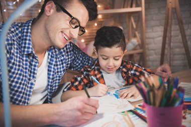 Baba ve oğul ile renkli kalemler evde kağıt üzerine çizim