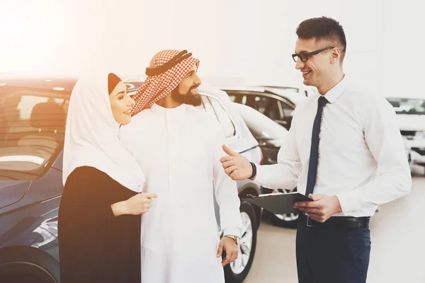 salesman help choosing new auto to Arabic couple at car dealership