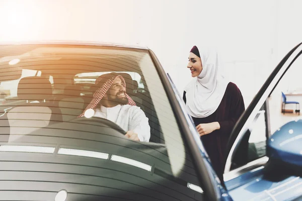 Arabic couple at car dealership, man and woman choosing new car