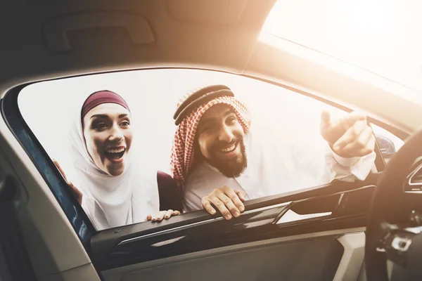 Arabic couple at car dealership, man and woman choosing new car