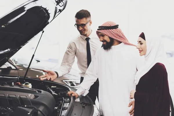 salesman help choosing new auto to Arabic couple at car dealership