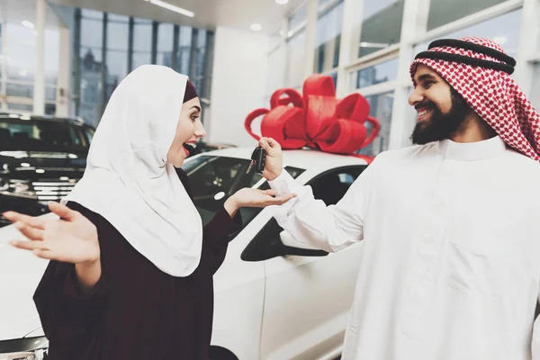 Arabic couple at car dealership, man presenting new car his wife