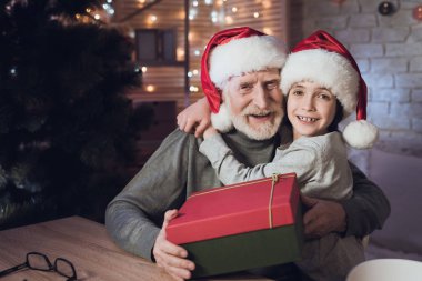 Dede ve torunu Noel Baba şapkaları içinde çocuk mevcut veren Dede