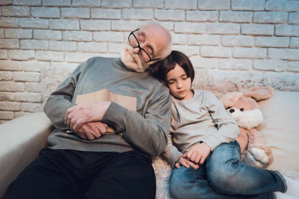 Grandfather and grandson sleeping sitting on couch at home