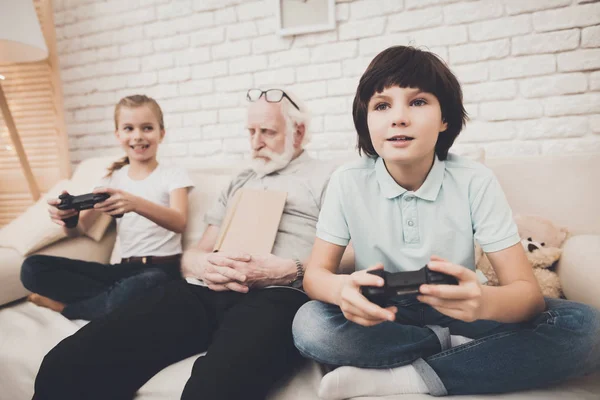 おじいちゃんが睡眠中のビデオゲームを遊んでいる子供たち — ストック写真