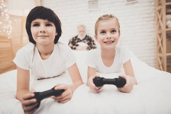 おじいちゃんが睡眠中のビデオゲームを遊んでいる子供たち — ストック写真