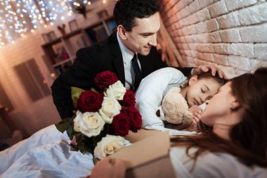 adam ile yatak küçük kızı anne kitap ile uyku sırasında koyarak gül buketi  