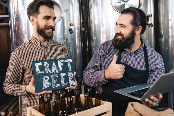 Dos Hombres Cervecería Mostrando Cartel Cerveza Artesanal —  Fotos de Stock