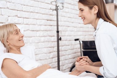 Kız yaşlı kadın evde yatakta ve onlar el ele tutuşarak bakmakta
