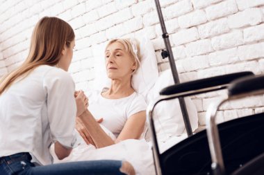 Hemşirelik ve yaşlı kadının o yatakta, yakın duran tekerlekli sandalye yalan sırasında elele kız