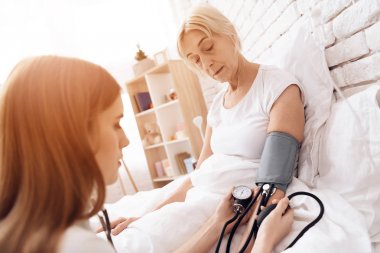 Yaşlı kadın Hemşirelik ve kan basıncı ölçmek için tonometer kullanarak kız