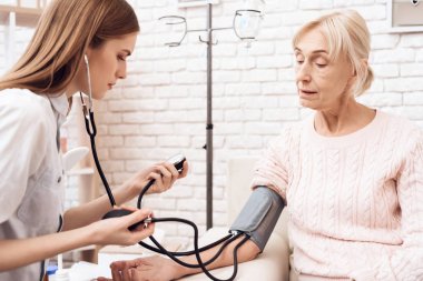 Yaşlı kadın Hemşirelik ve kan basıncı ölçmek için tonometer kullanarak kız