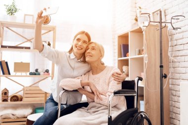 Yaşlı kadın evde tekerlekli sandalyede bakmakta ve selfie smartphone alarak kız 