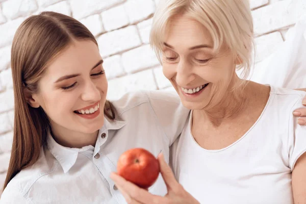 Niña Amamantando Anciana Cama Casa Abrazando Pensionista Sosteniendo Manzana —  Fotos de Stock