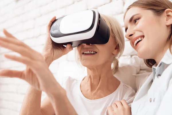 Girl nursing elderly woman at home and they using virtual reality
