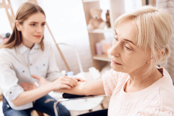 Девочка кормит пожилую женщину в инвалидной коляске дома и с помощью счетчика
 