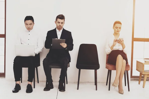 HR director woman in blouse and skirt sitting with coworkers on chairs