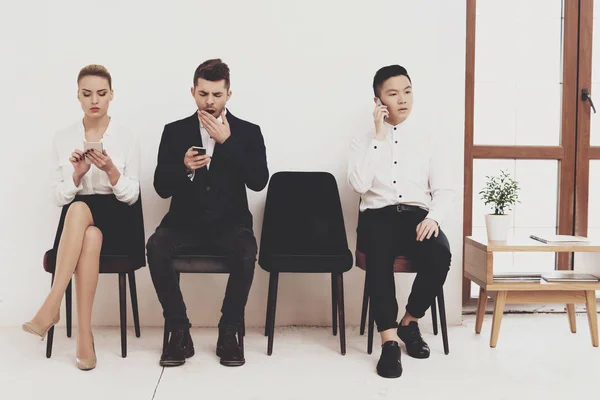 HR director woman in blouse and skirt sitting with coworkers in waiting room