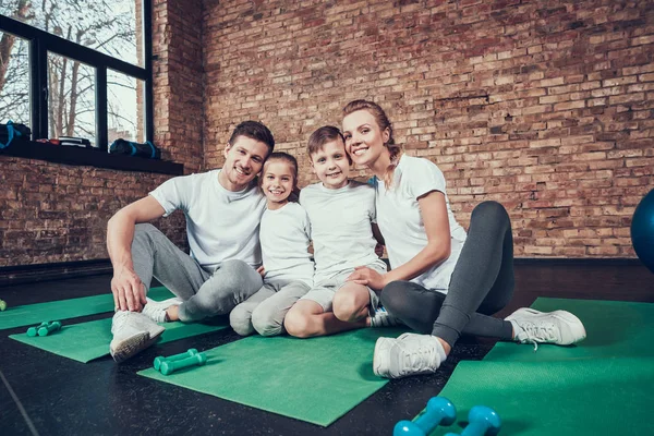 在健身房训练后快乐的家庭坐在绿色的垫子上 — 图库照片