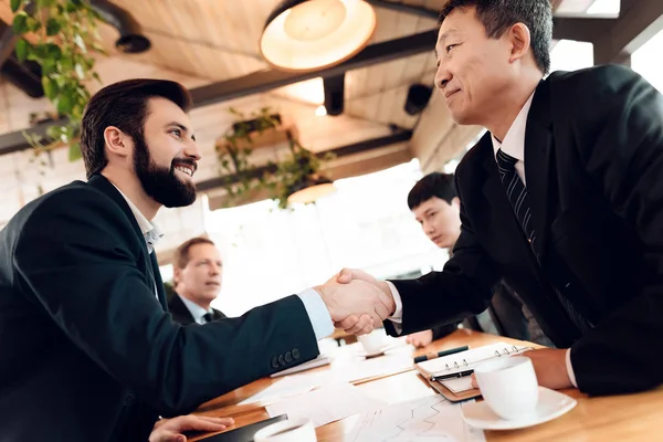 businessmen meeting in restaurant and shaking hands