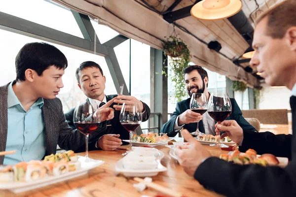 Men drinking wine on meeting with Chinese businessmen in restaurant