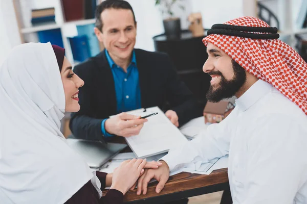 Arab couple signing contract of sale in office of realtor, concept of house buying