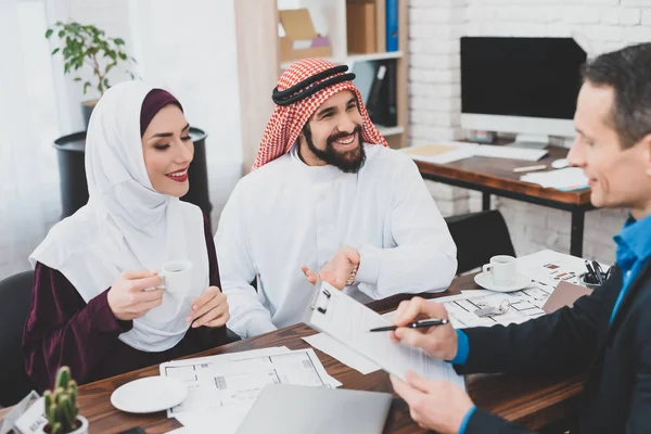 Realtor reading terms of purchase and sale agreement for young Muslim couple