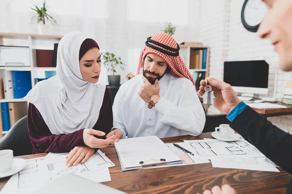Arab couple in national clothes reading contract of sale thoughtfully at real estate agency