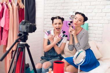 Kamera için farklı fırçalar sunan iki moda blogger kız