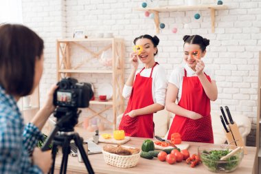 Kırmızı önlüklü iki mutfak blogcusu kameraya doğranmış biber tutuyor..