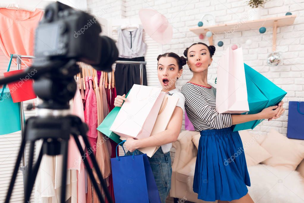 Two fashion blogger girls posing with colorful bags on camera