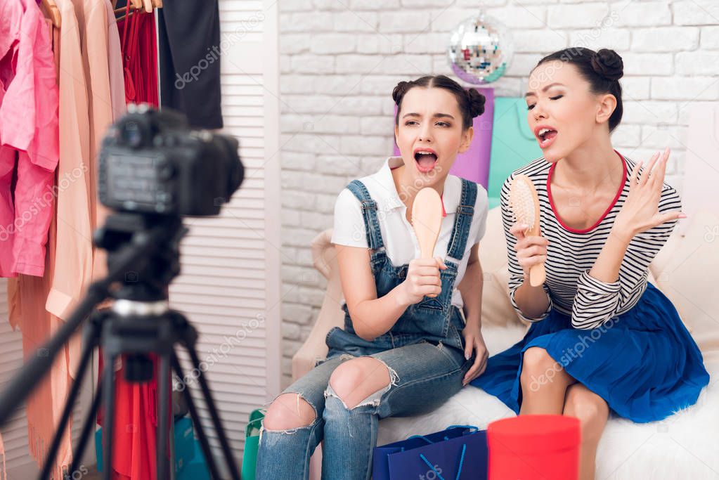 Two fashion blogger girls holding combs singing to camera