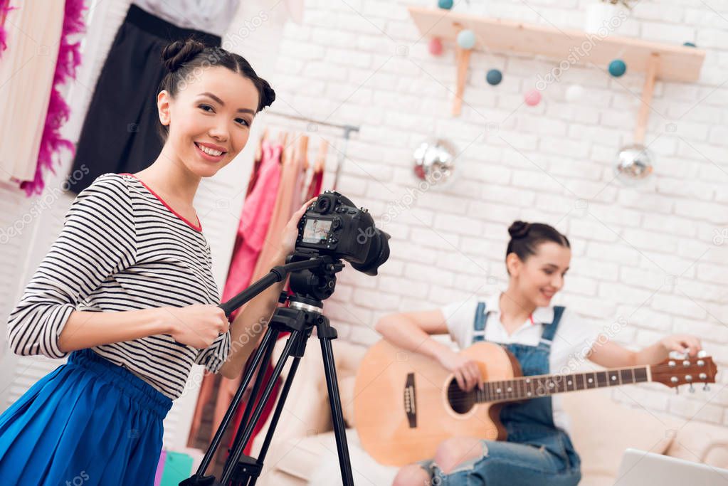 Two female fashion bloggers play guitar, girl behind camera