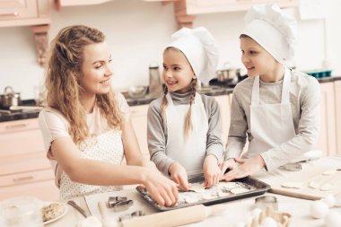 Çocuk beyaz şapka ve anne Mutfak at hamur çerezlerini yaptırıyor