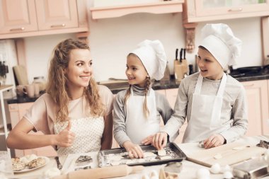 Çocuk beyaz şapka ve anne Mutfak at hamur çerezlerini yaptırıyor