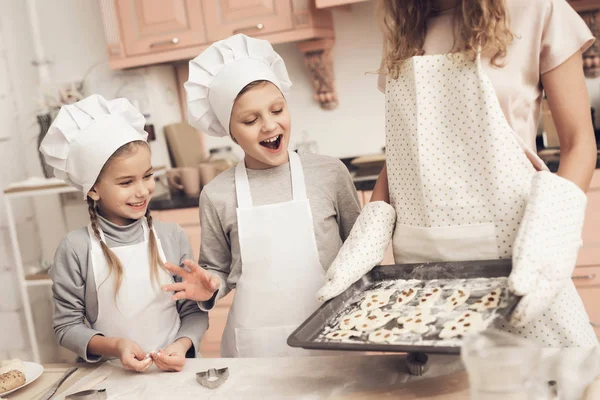 儿童在厨房和母亲的白色帽子拿着饼干托盘 — 图库照片